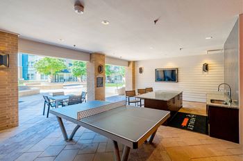 A ping pong table is in the middle of a room with a tv and a counter.
